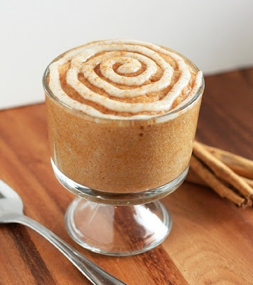 A cinnamon roll mug cake in a glass topped with frosting