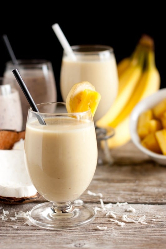 pina colada protein smoothie in glass with a straw