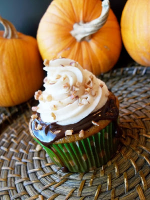 Pumpkin cupcake with chocolate ganache and spiced cream cheese frosting with pumpkins in the background