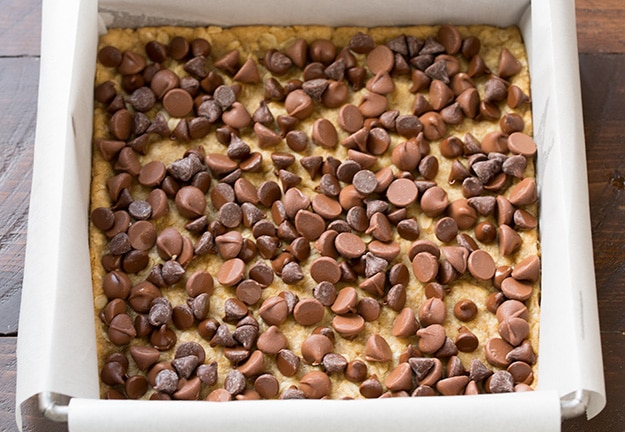 chocolate chips atop oatmeal cookie base in baking pan