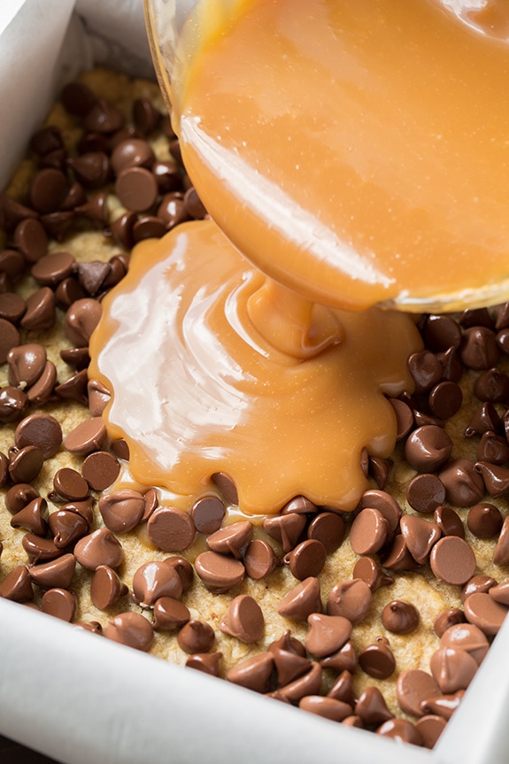 pouring caramel over a layer of chocolate chips