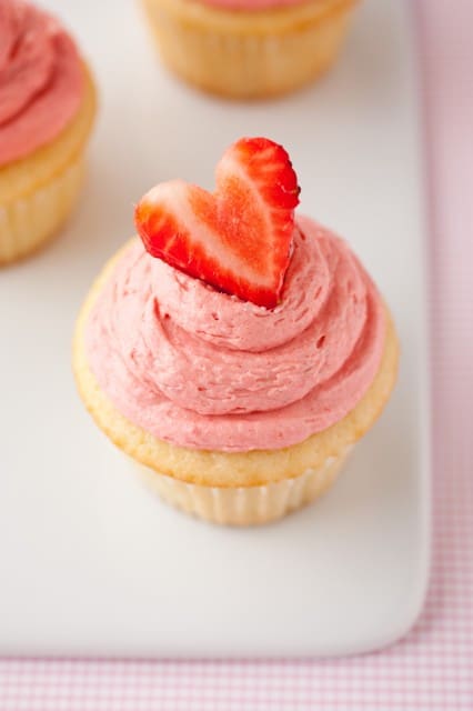Strawberry Shortcake Cupcake topped with strawberry buttercream and a sliced strawberry 