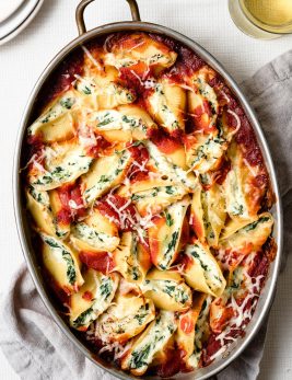 Stuffed Shells in a large oval baking dish. They're filled with cheese and spinach and covered with marinara sauce.