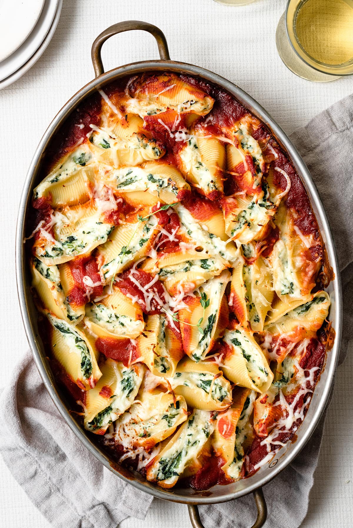 Stuffed Shells in a large oval baking dish. They're filled with cheese and spinach and covered with marinara sauce. 