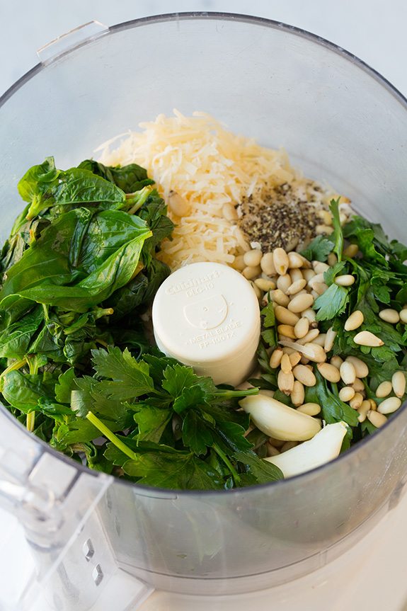 homemade pesto ingredients in bowl of food processor 