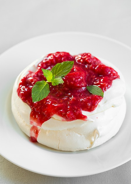 Individual pavlovas with cream cheese whipped cream and raspberry sauce
