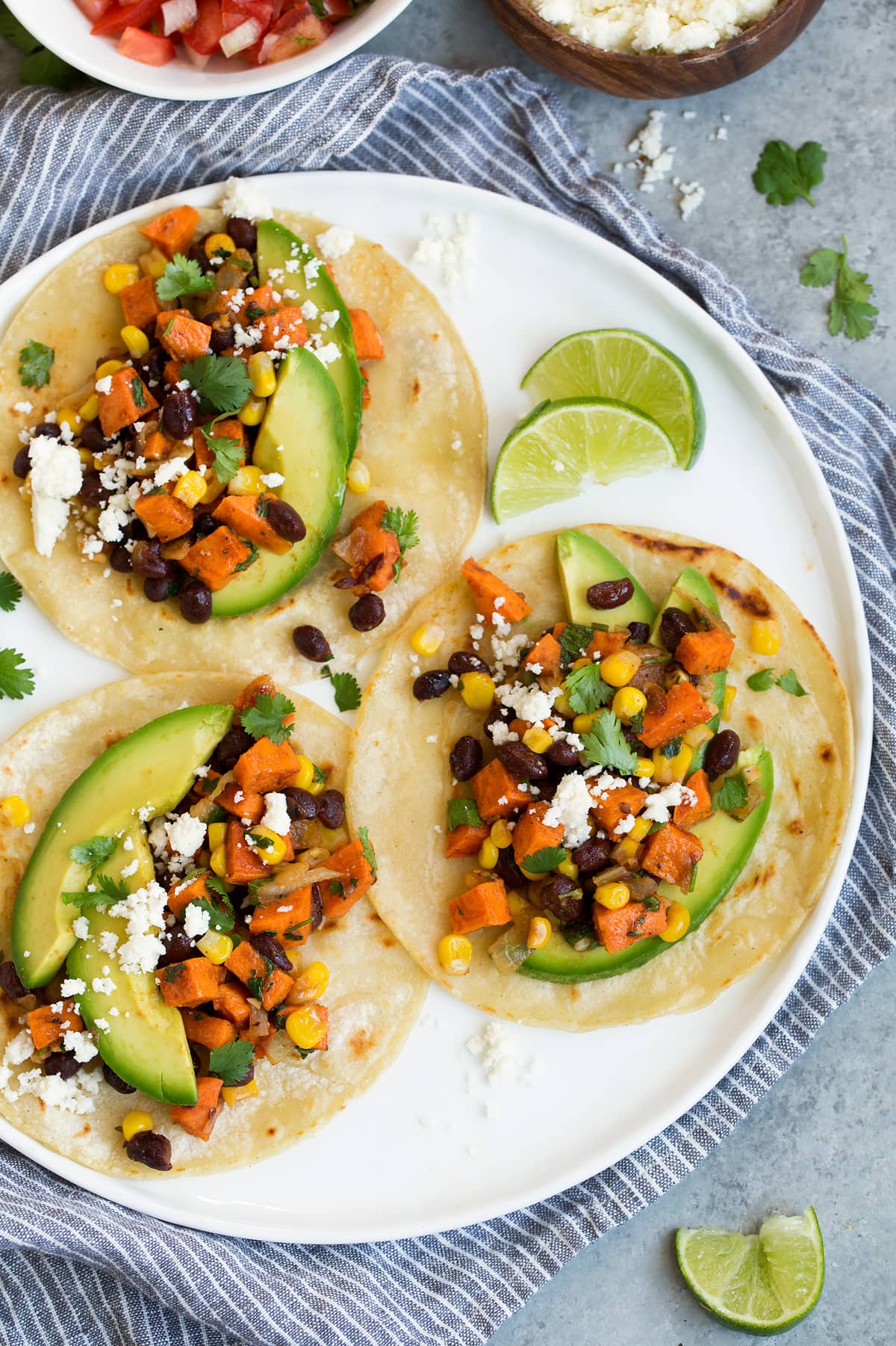 Three healthy sweet potato and black bean tacos on white plate. 