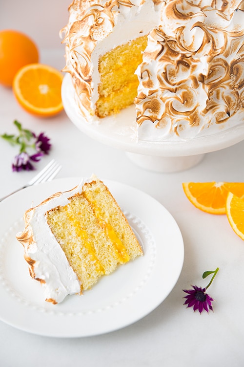 slice of Orange Chiffon Cake with Orange Filling and Meringue next to cake on a cake stand