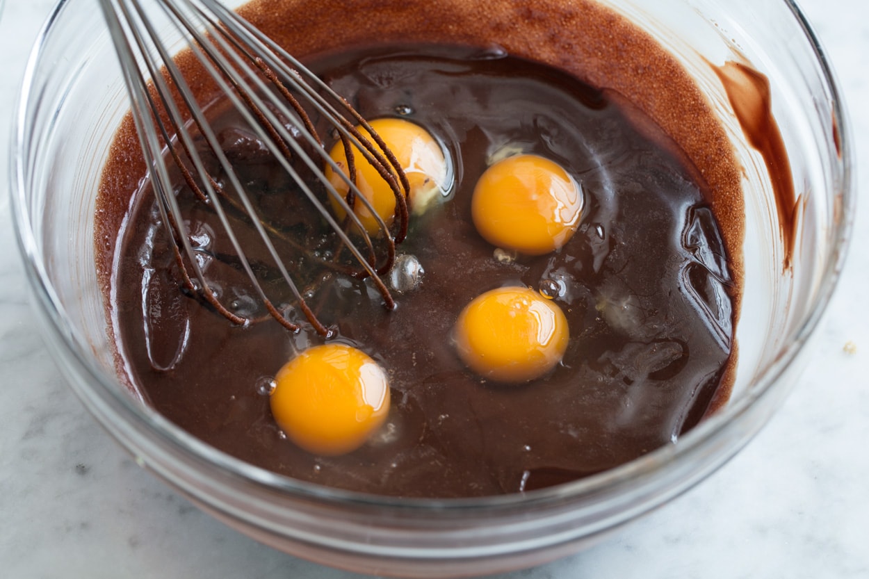 Whisking eggs into flourless chocolate cake mixture in mixing bowl.
