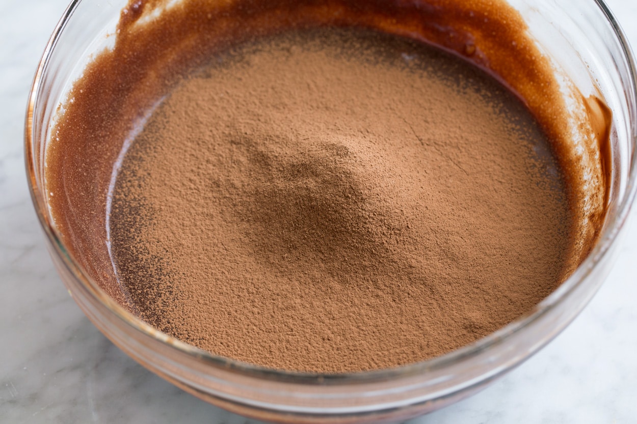 Sifting cocoa powder into flourless chocolate cake batter.