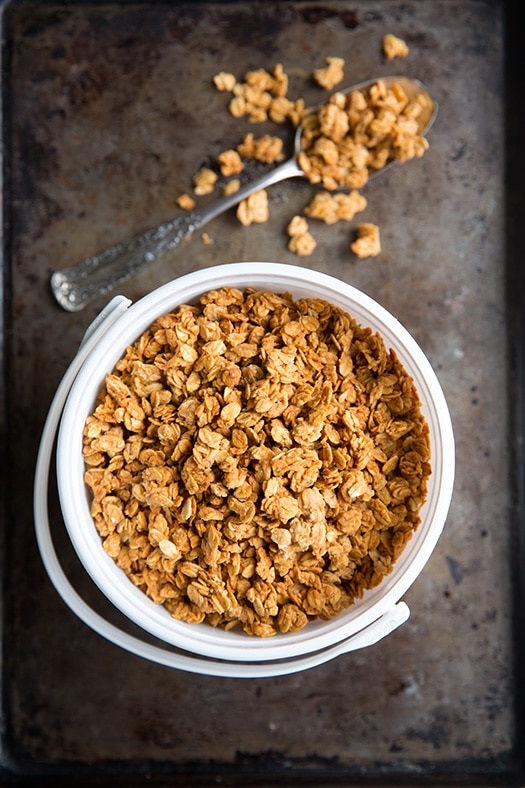 Peanut Butter Granola in a white bowl next to a spoon