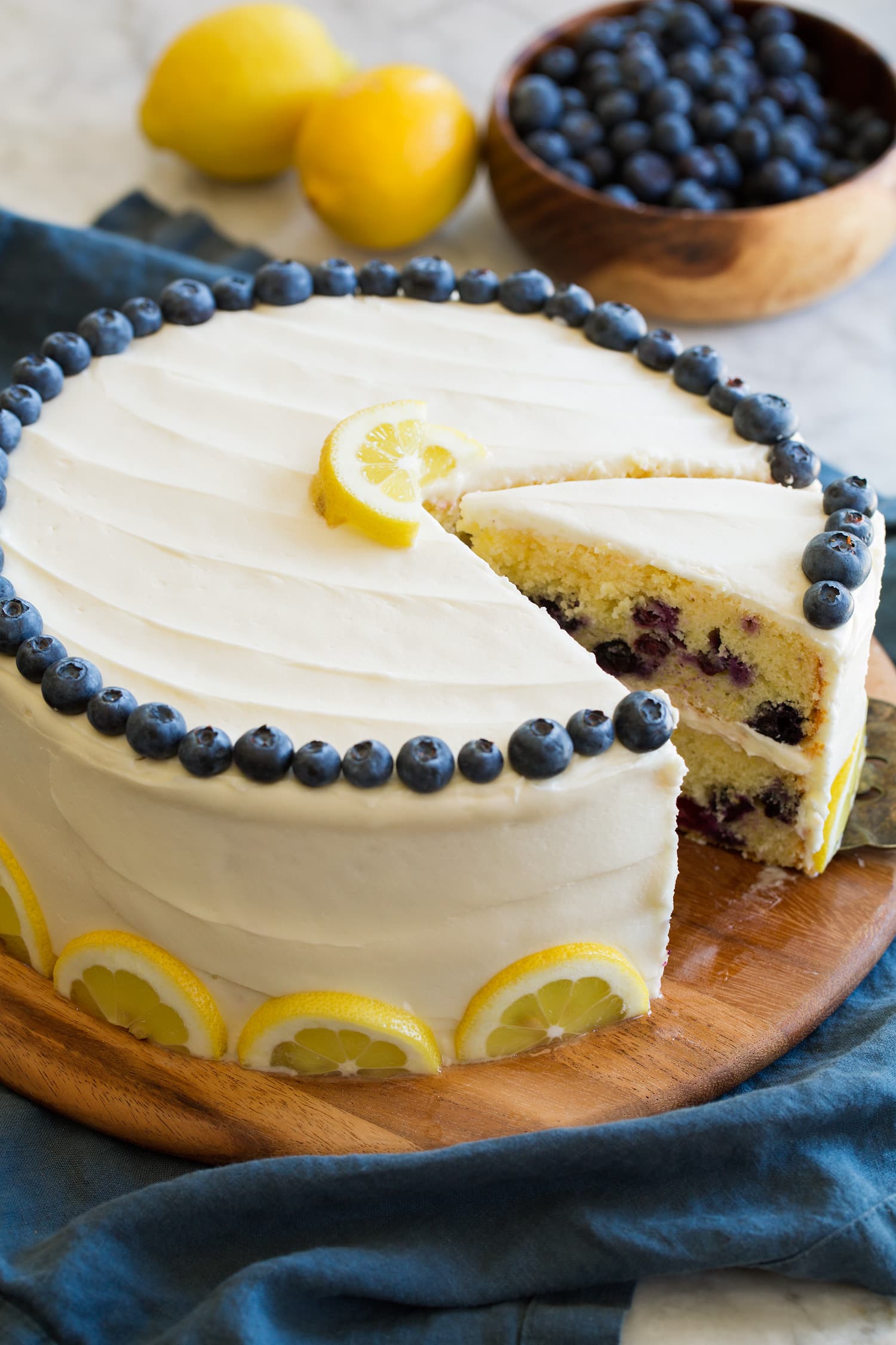 Whole cake with sliced removed. Garnished with fresh blueberries and lemon slices.