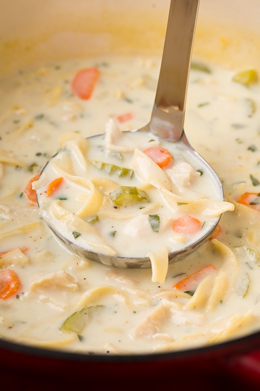 A close up of a ladel of Creamy Chicken Noodle Soup in a pot