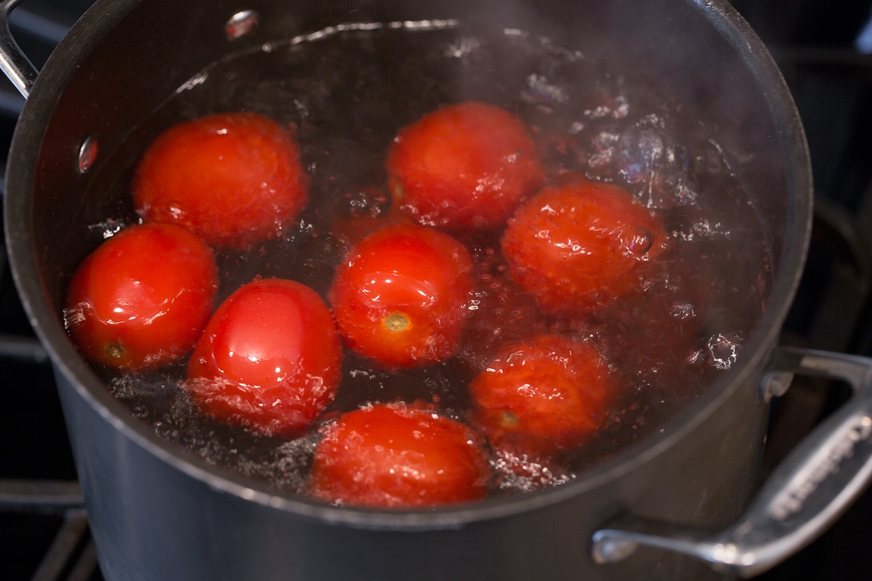Boiling tomatoes in a large pot for tortellini soup.