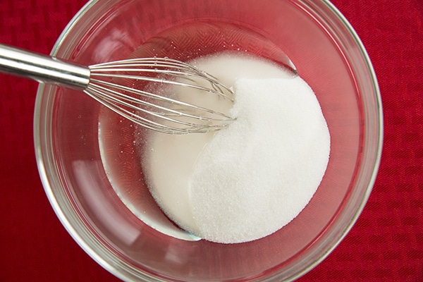Whisking sugar and corn syrup in a bowl.