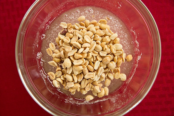 Stirring peanuts into mixture in mixing bowl.