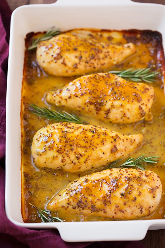 Baked Honey Mustard Chicken with sprigs of fresh rosemary in a white baking dish