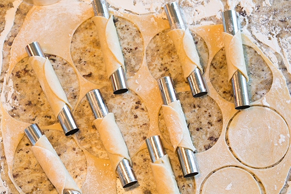 How to make Cannoli - wrapping cannoli dough around cannoli shell forms