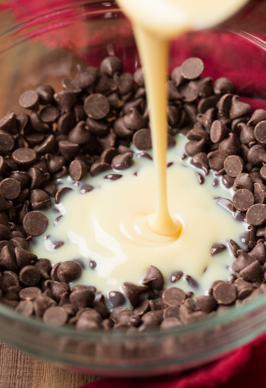 pouring sweetened condensed milk into bowl of chocolate chips