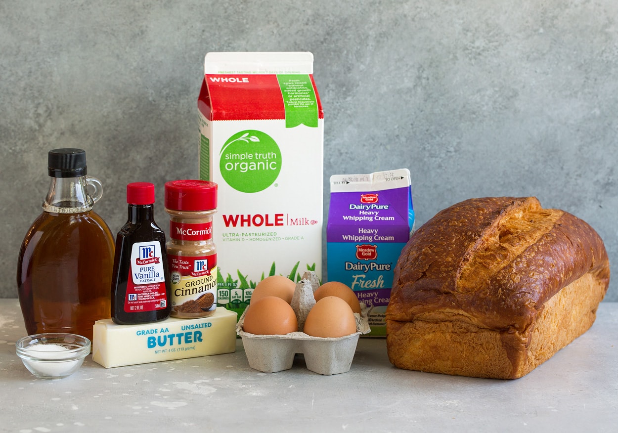 Ingredients needed to make french toast shown here including fresh bread, eggs, milk, cream, vanilla, cinnamon, butter, sugar and maple syrup.