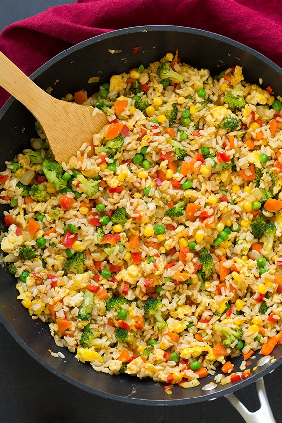 Veg fried rice in a skillet with wooden spoon