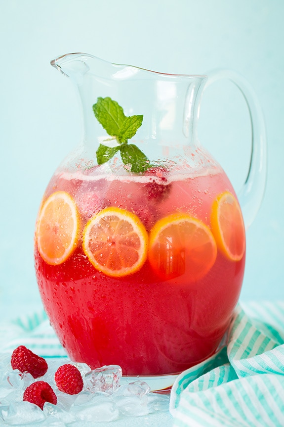 Sparkling Raspberry Lemonade in glass pitcher with sliced lemon and mint leaves