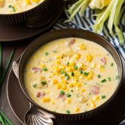 Corn Chowder in two serving bowls. Chowder has fresh pieces of corn, chunks of ham and is garnished with chives.