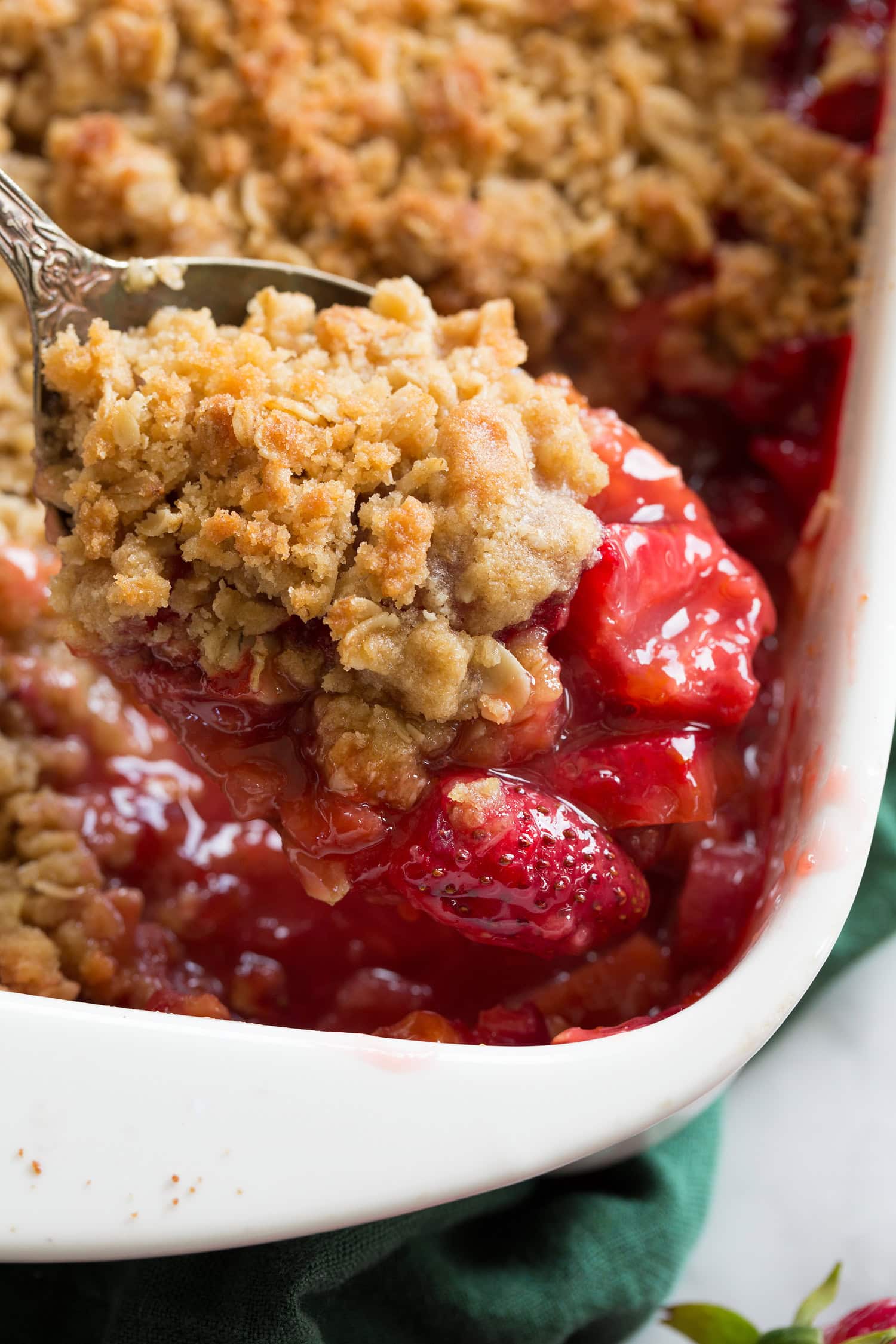 Close up photo of strawberry rhubarb crisp in a large serving spoon.