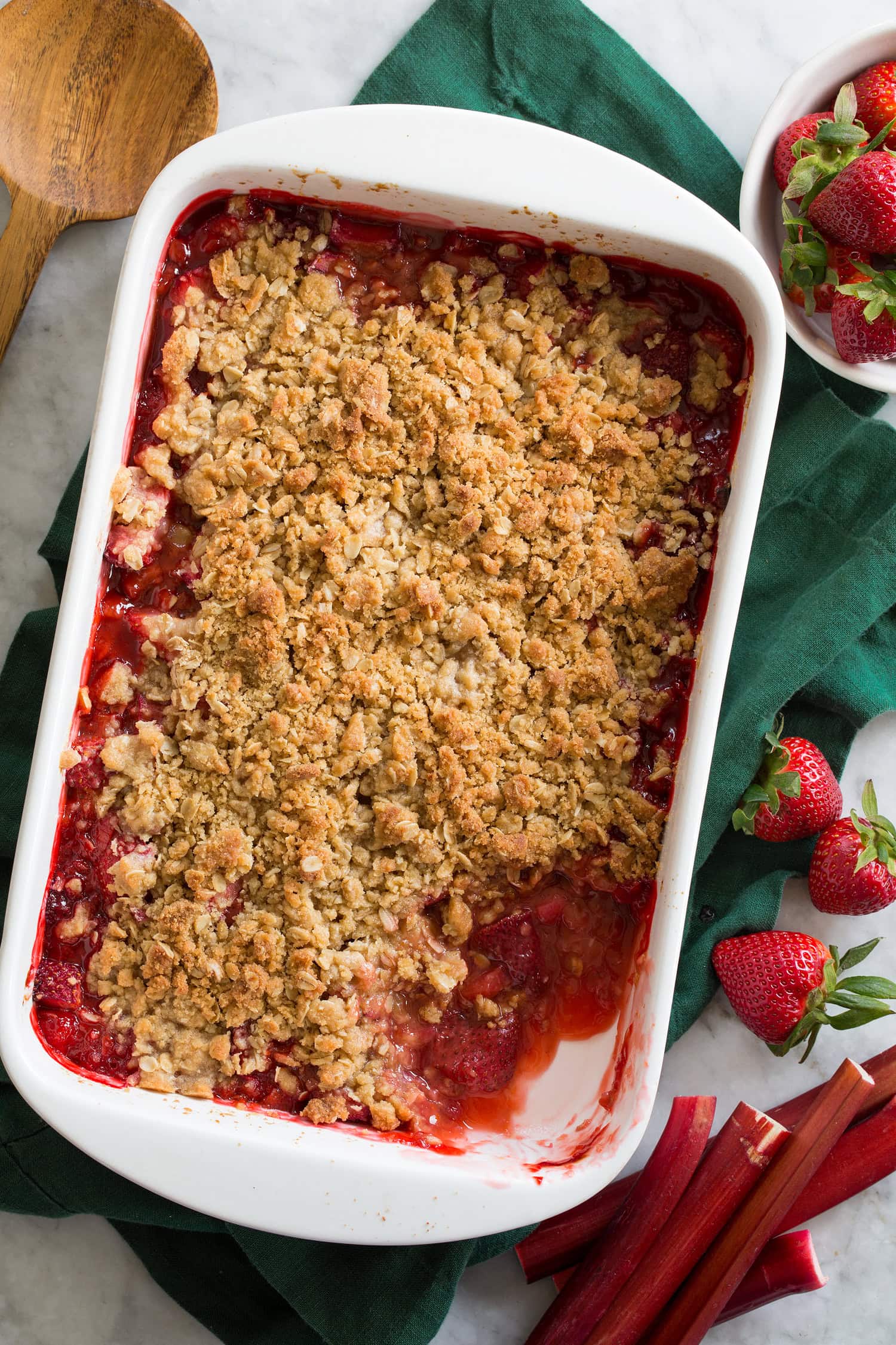 Overhead photo of strawberry rhubarb crisp in a baking dish with one scoop removed.