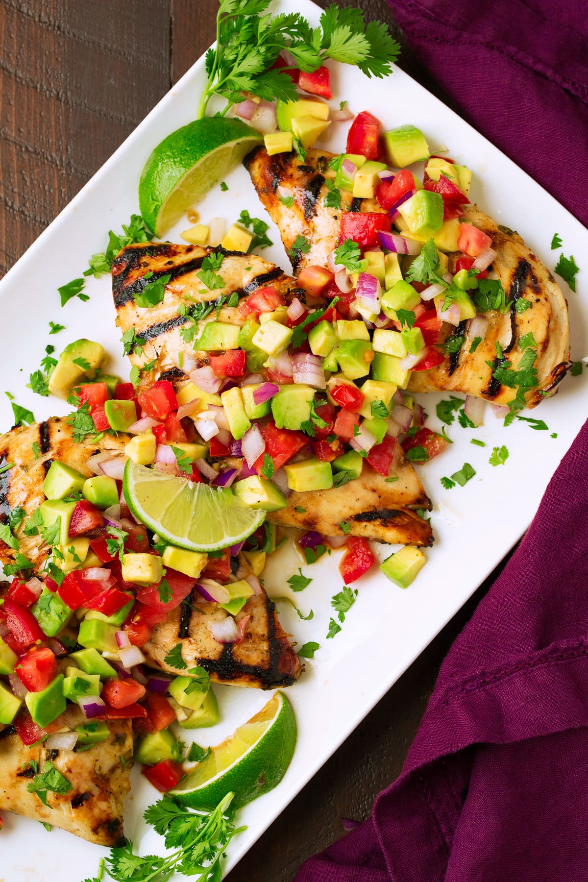 four Cilantro Lime Chicken breasts topped with avocado salsa on white platter
