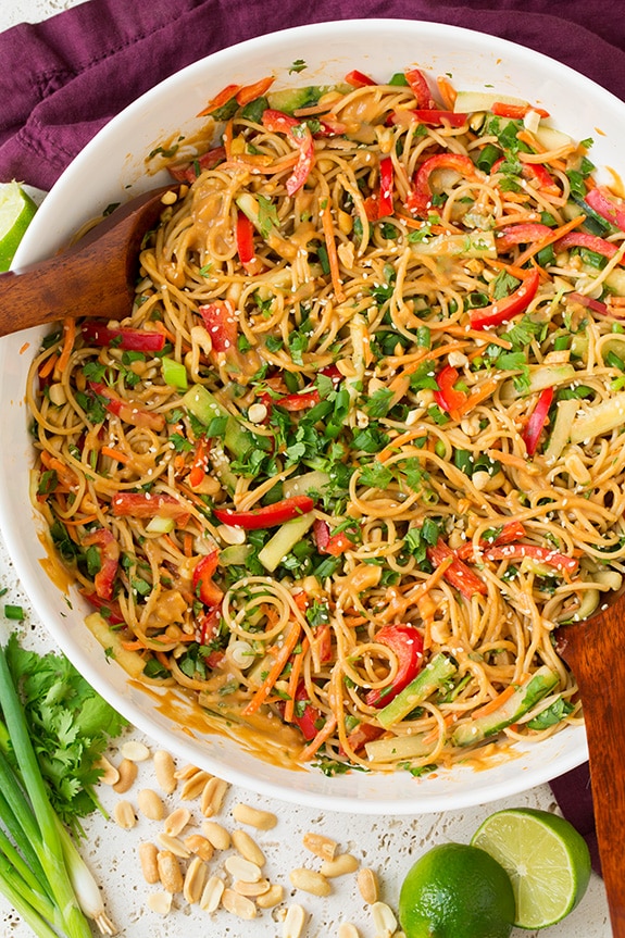 Spicy Thai Peanut Noodles in white bowl with serving spoons