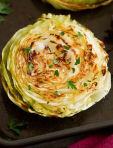 Photo: A roasted cabbage slice is shown from close up. It is golden brown and garnished with parsley.