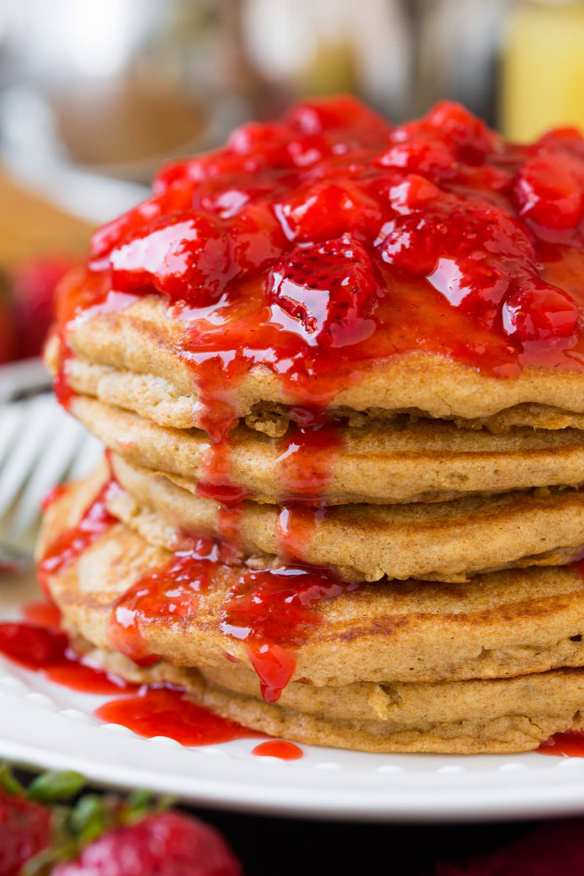 Healthy whole wheat pancakes topped with honey sweetened strawberry syrup.