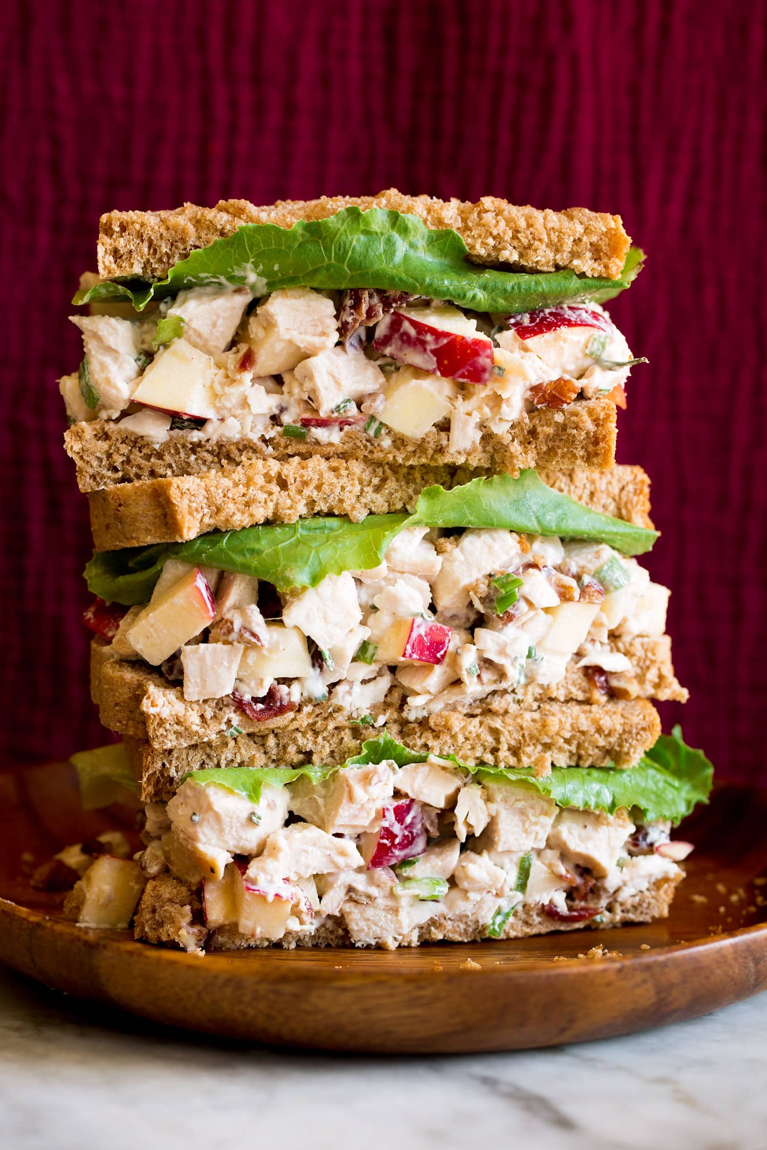 Chicken salad with apples shown in whole wheat bread slices as stacked sandwiches.