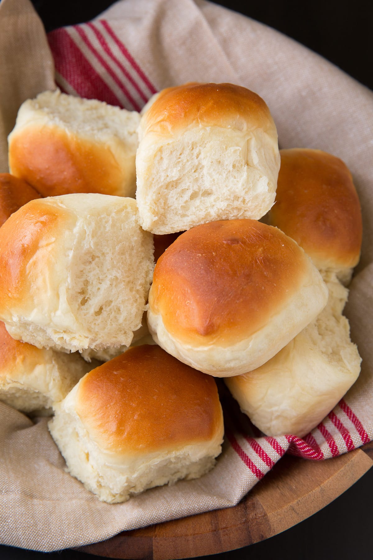 Dinner Rolls shown in a wooden bowl resting on a kitchen cloth.