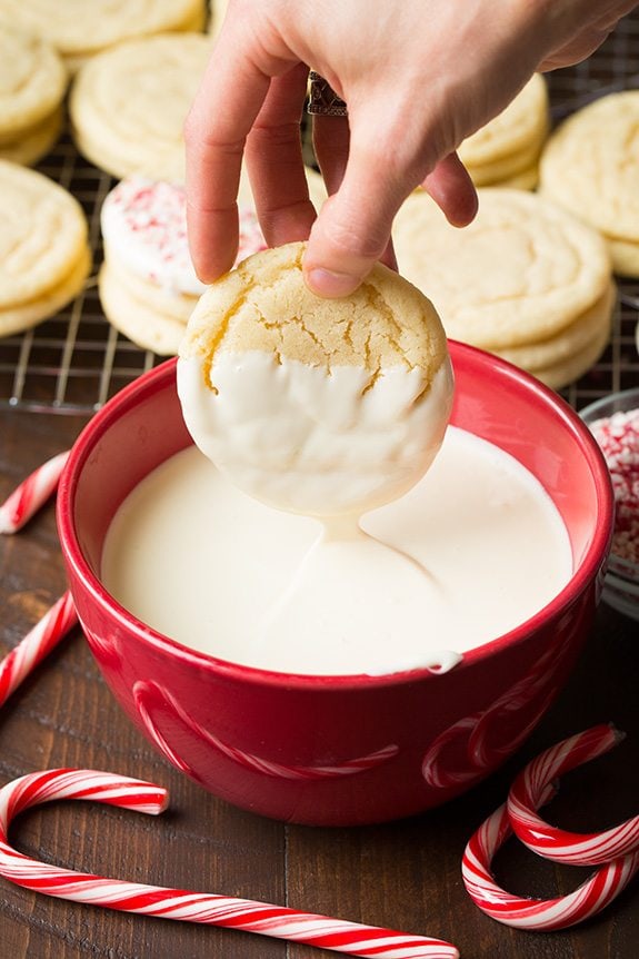 Dipping a sugar cookie into a bowl of melted white chocolate.