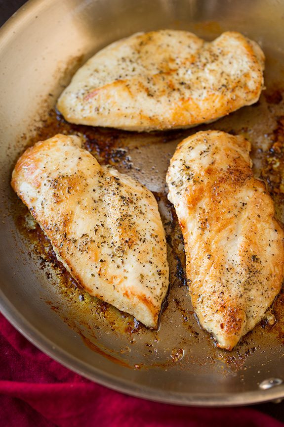 Three browned seasoned chicken breasts shown here in a skillet after cooking