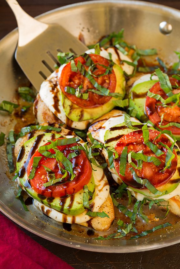 Shown here chicken breasts in a skillet are top with fresh mozzarella avocado tomato basil and balsamic glaze
