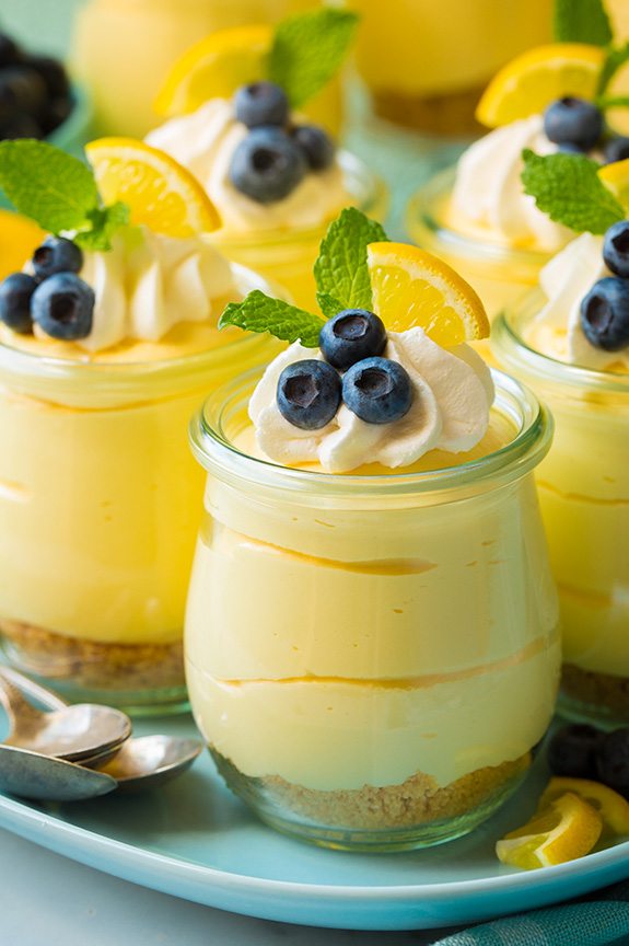 Lemon mousse in a glass topped with whipped cream, blueberries and lemon