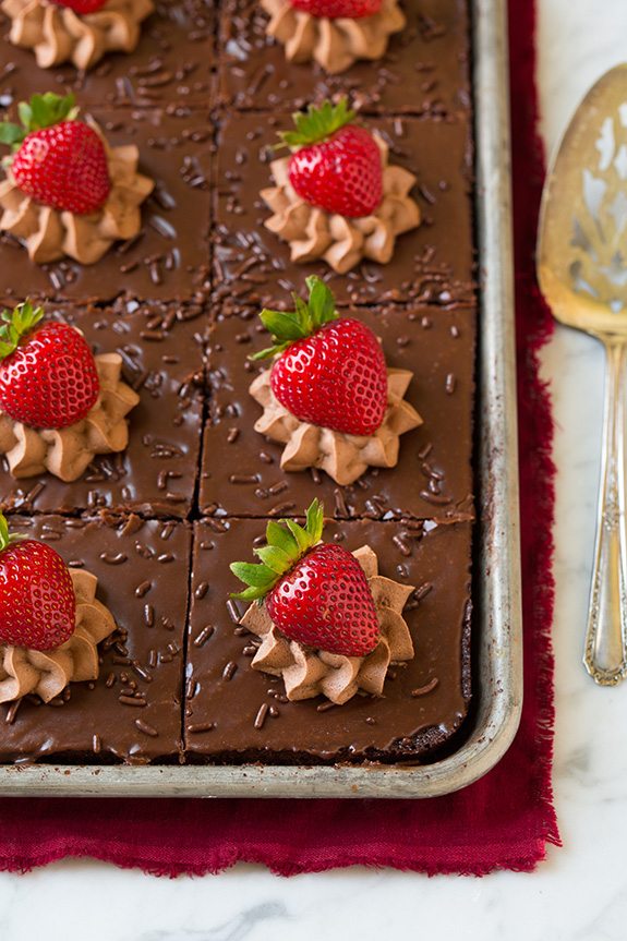 Best chocolate cake cut into squares and topped with chocolate mousse and strawberries