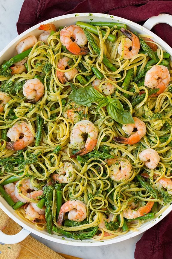shrimp pesto pasta with asparagus garnished with basil leaves
