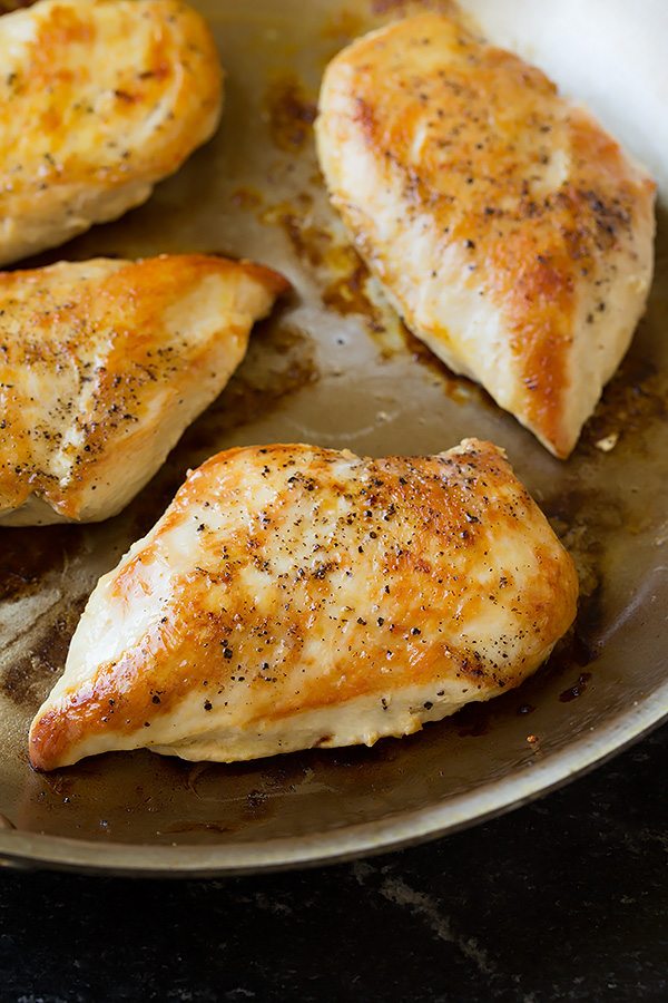 Four pan seared chicken breasts in a skillet.