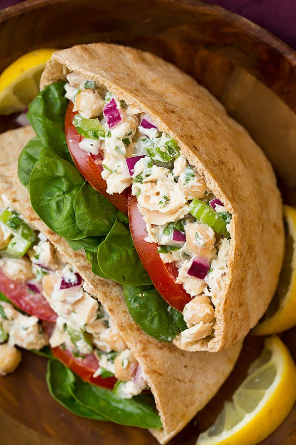Tuna Sandwiches. Tuna Salad is layered in pita bread with tomatoes and spinach. Shown served in a wooden bowl.