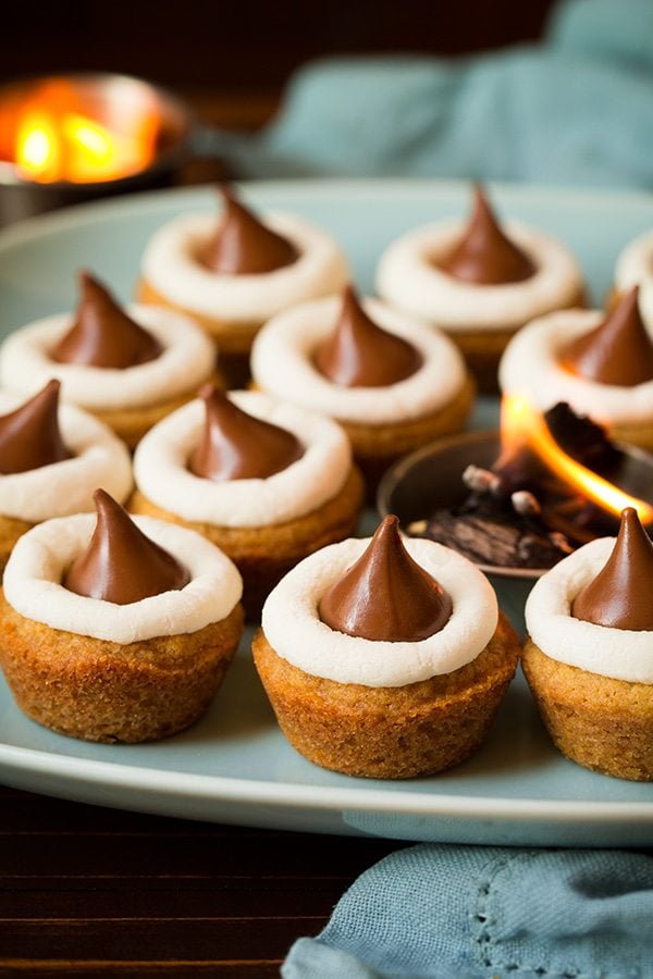 Mini S'mores Cookie Cups on a turquoise plate with a small fire in a cup in the center.