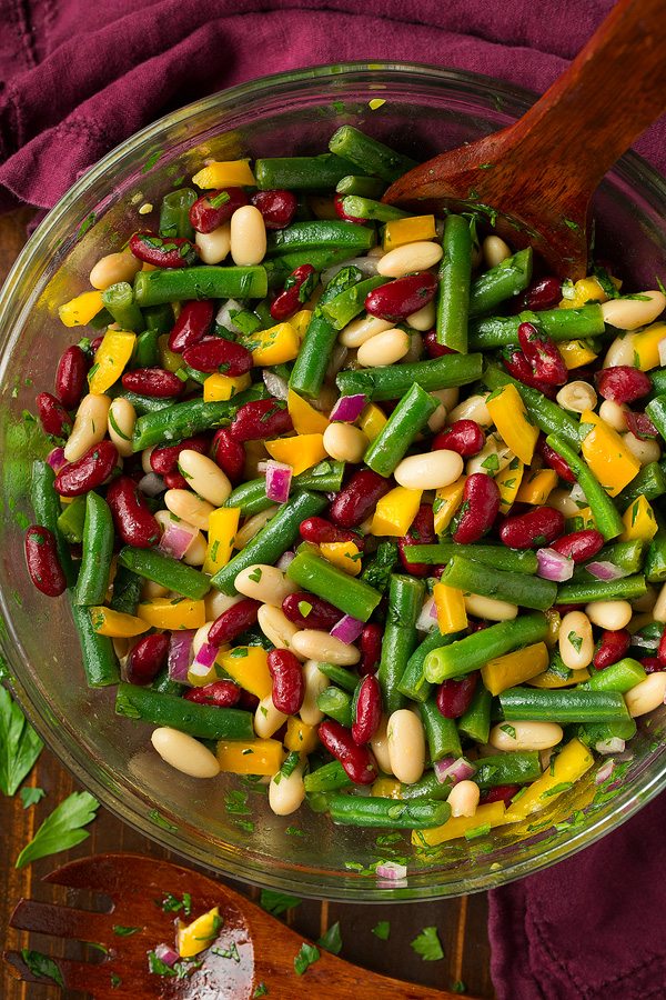 Three Bean Salad in a glass mixing bowl. Includes dark and light kidney beans, bell pepper, onion and a vinaigrette dressing.