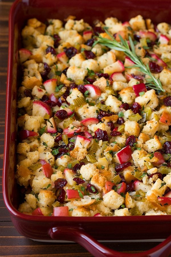 Stuffing in a red baking dish with apples, cranberries and herbs.