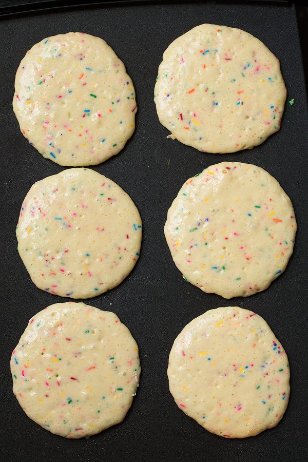 Funfetti pancakes batter on griddle in 6 round portions.