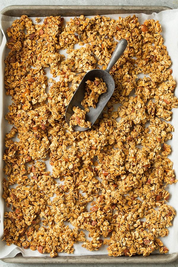 Granola on a parchment paper lined baking sheet after cooking.