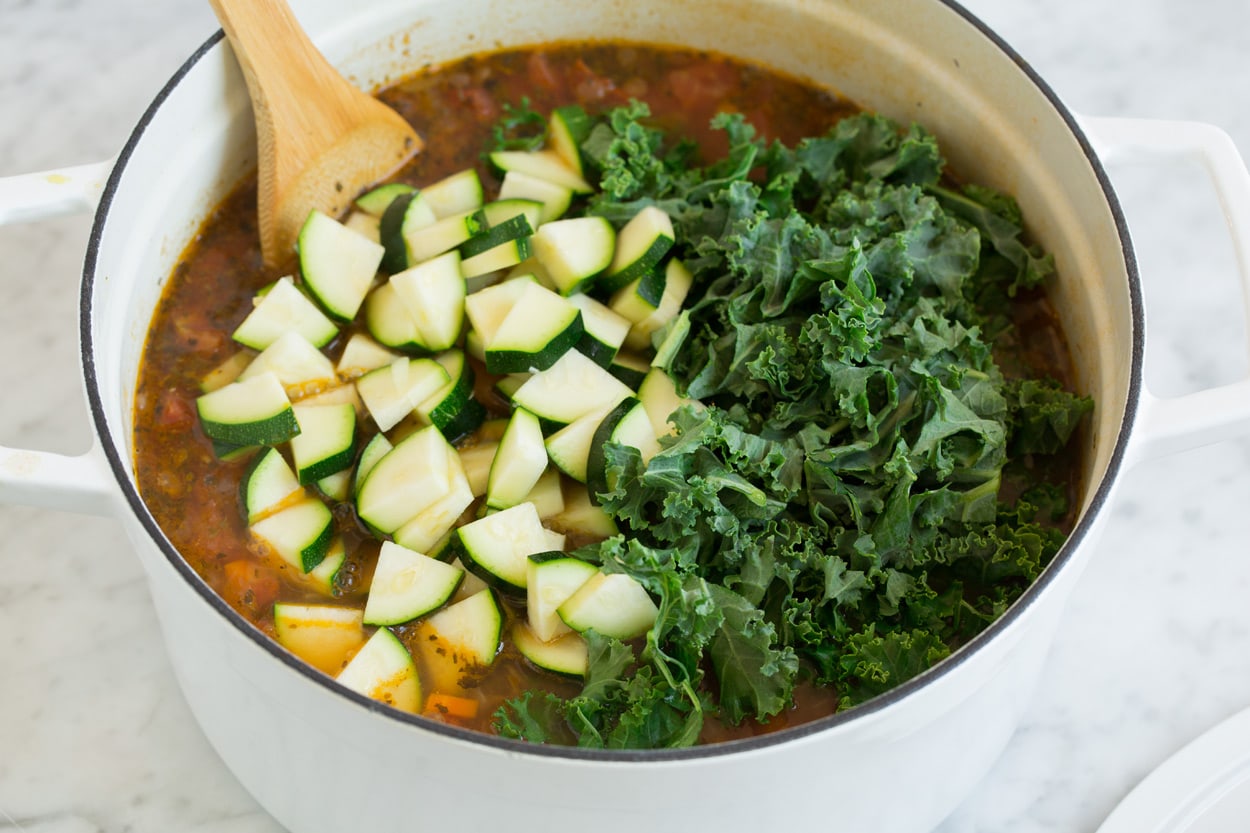 zucchini and kale in a pot of lentil soup