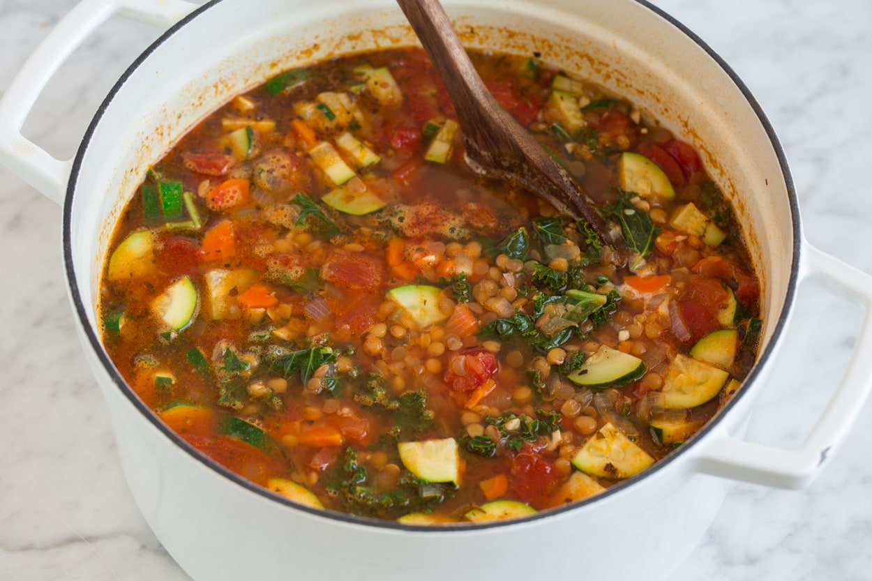lentil soup full of vegetables in a large cast iron pot